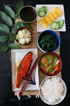 a table topped with plates and bowls filled with different types of food next to chopsticks