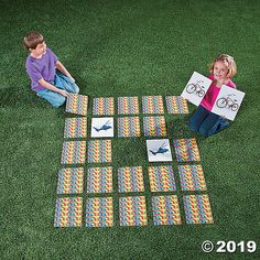 two children sitting on the grass playing with blocks