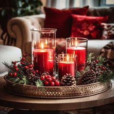 three candles are sitting on a tray with holly and pine cones in it, surrounded by red berries