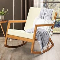 a rocking chair with a blanket on it in front of a window and potted plant