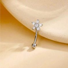 a close up view of a single flower shaped nose ring with clear stones on it