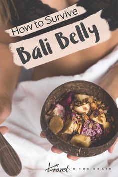 a person holding a bowl with food in it and the words how to survive bali belly