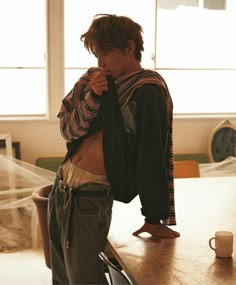 a young man standing on top of a wooden table next to a bag and coffee cup