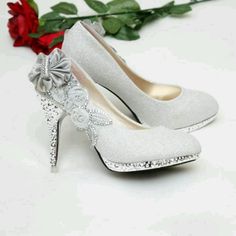 a pair of white high heeled shoes sitting next to a rose