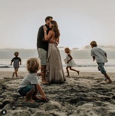 a man and woman kissing on the beach with children