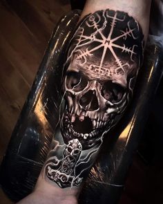 a man's arm with a skull and cross tattoo on it, while he is sitting