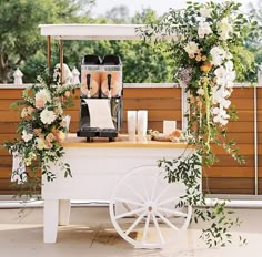 an outdoor wedding ceremony with flowers and greenery on the table, along with a white wagon filled with bride's shoes