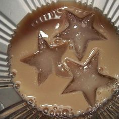 three star shaped chocolates are in a tin foil container with liquid on the bottom