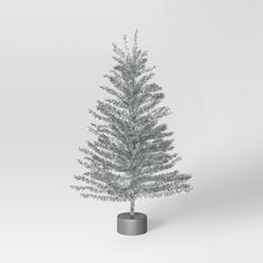 a small silver christmas tree in a gray pot on a white background with copy - space