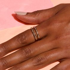 a woman's hand with two gold rings on top of her finger and one in the middle