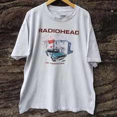 a white t - shirt with the words radiohead on it hanging from a wooden hanger