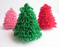 three small crocheted christmas trees sitting next to each other on a white surface