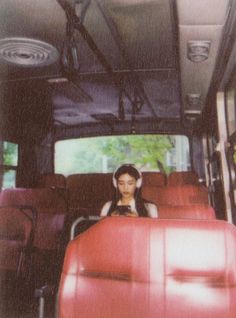 a woman sitting in the back of a red bus