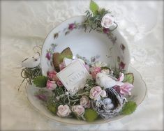 there is a plate with flowers and birds in it on top of a lace tablecloth