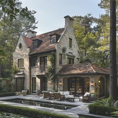 a large stone house with a pool in the front yard and patio area next to it