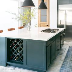 a kitchen with an island and wine rack in the center, along with two pendant lights hanging from the ceiling