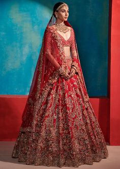 a woman in a red lehenga with gold jewelry on her neck and shoulders