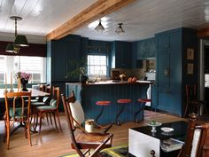 an open kitchen and dining room area with blue walls, wood flooring and wooden chairs