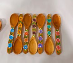 six wooden spoons with painted flowers on them are lined up next to each other