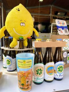 a yellow stuffed animal sitting on top of a table next to beer bottles and glasses