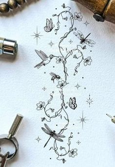 a tattoo design with flowers and butterflies on paper next to scissors, ink pens and other items