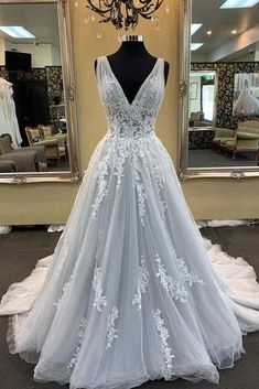 a white wedding dress on display in front of a mirror with a large mirror behind it