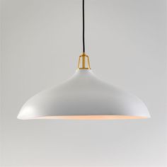 a large white light hanging from a black cord on a gray wall in a room