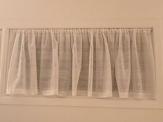 a window with white curtains hanging on the wall