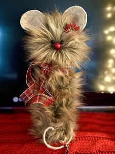 a small stuffed animal is sitting on a red blanket with lights in the back ground