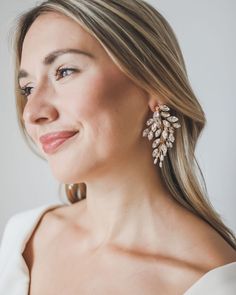 a woman with blonde hair wearing large gold and crystal earring set on her left ear