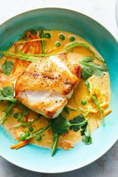 a blue bowl filled with fish and vegetables