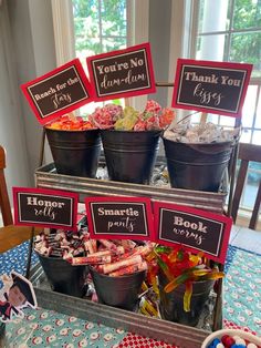 a table topped with buckets filled with candies and other candy items on top of it