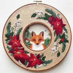 an embroidery project with a red fox surrounded by poinsettis and greenery