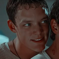 two young men are looking at the camera with blue eyes and piercings on their neck