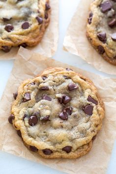 three chocolate chip cookies sitting on top of brown paper