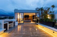 an outdoor living area with wooden flooring and lighting on the side of the house