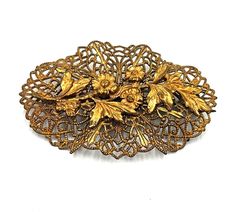 This vintage brass filigree brooch/pin is a stunning piece of jewelry. The brooch has a filigree base with a flower and leaf design on the top, adding a touch of elegance and charm. The brooch is in excellent condition with a firmly working clasp, ensuring that it stays securely in place. This brooch is a perfect addition to any collection of vintage jewelry or as a statement piece for everyday wear. The intricate detailing and unique design make it a one-of-a-kind piece that is sure to catch the eye. Details: Vintage brass filigree brooch/pin Beautifully intricate design with flower and leaf detailing Excellent condition with a firmly working clasp A perfect addition to any collection of vintage jewelry or as a statement piece for everyday wear Unique design that is sure to catch the eye Victorian Filigree Brooches For Vintage Events, Vintage Gold Brooches With Intricate Design, Vintage Gold Brooch With Intricate Design, Vintage Filigree Flower Brooches, Art Nouveau Wedding Brooches With Filigree, Ornate Flower Brooch With Filigree, Brass Filigree, Leaf Design, A Flower