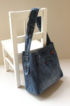 a white chair with a blue jean purse hanging from it's back end,