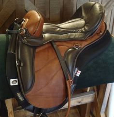 a close up of a horse saddle on a wooden floor with green velvet padding