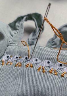 an embroidered piece of cloth being sewn on by a pair of scissors and thread