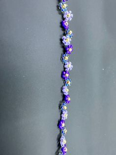 a purple and blue necklace with flowers on it