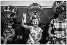 three women and two children with hair rollers on their heads sitting in a booth