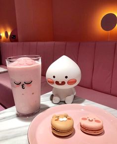 there is a pink plate with two macaroons and a drink on the table