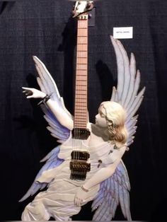 a statue of an angel holding a guitar with wings on it's back and body