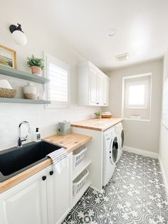 a washer and dryer in a small room with tile flooring on the walls