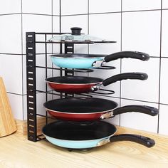 pots and pans are stacked on a rack in front of a wall tile background