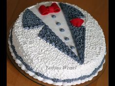 a cake decorated with white frosting and red bow ties on a wooden table top