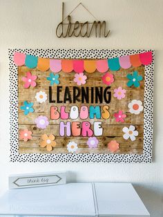 a sign that says learning blooms here hanging on the wall above a dryer in a laundry room