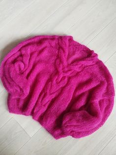 a pink sweater laying on top of a white floor