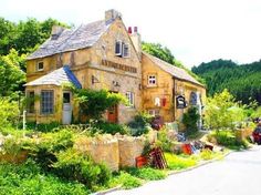 an old stone building sitting on the side of a road next to lush green trees